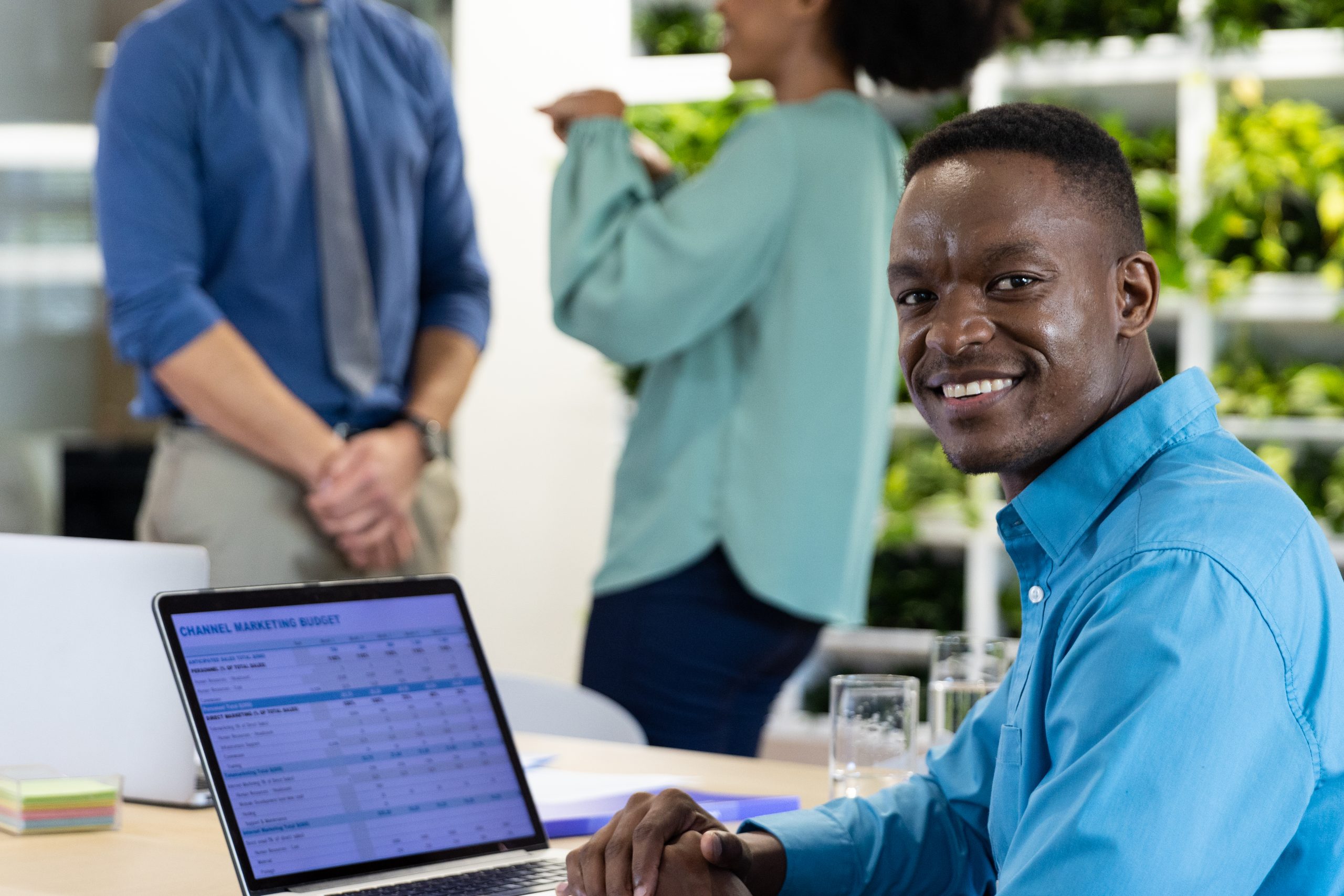 Portrait of happy african american businessman with laptop and diverse colleagues in modern office. Global business, finances and office concept.
